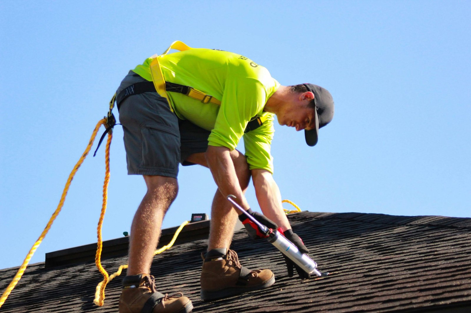 a man in a yellow shirt is working on a roof